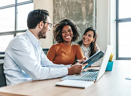 Three people discuss in front of a laptop