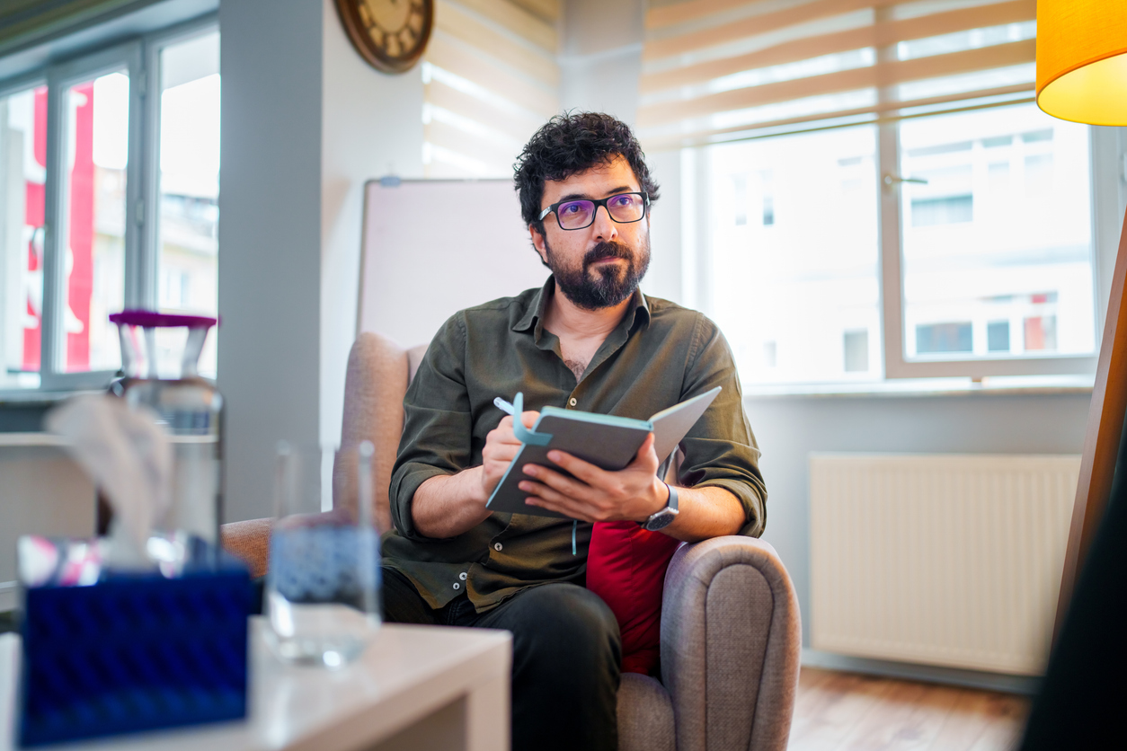 A psychology researcher sits at a desk and writes in a notebook