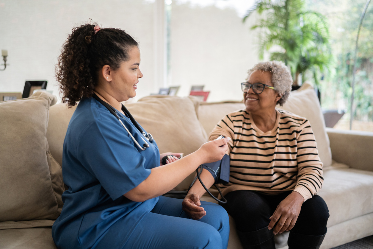 A home health nurse takes a patient’s blood pressure.