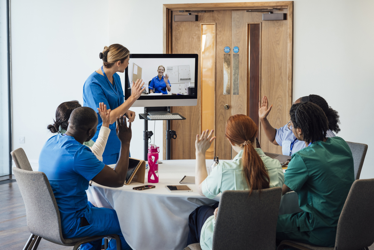 A nurse manager meets with a distributed nursing team on a video call.
